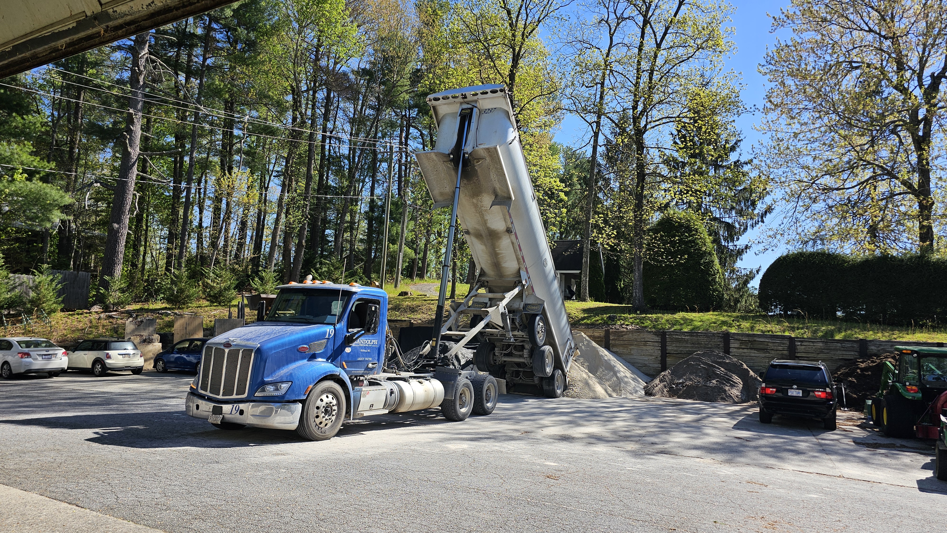 Blue semi-truck delivering a load of sand to the maintenance yard with trailer raised.