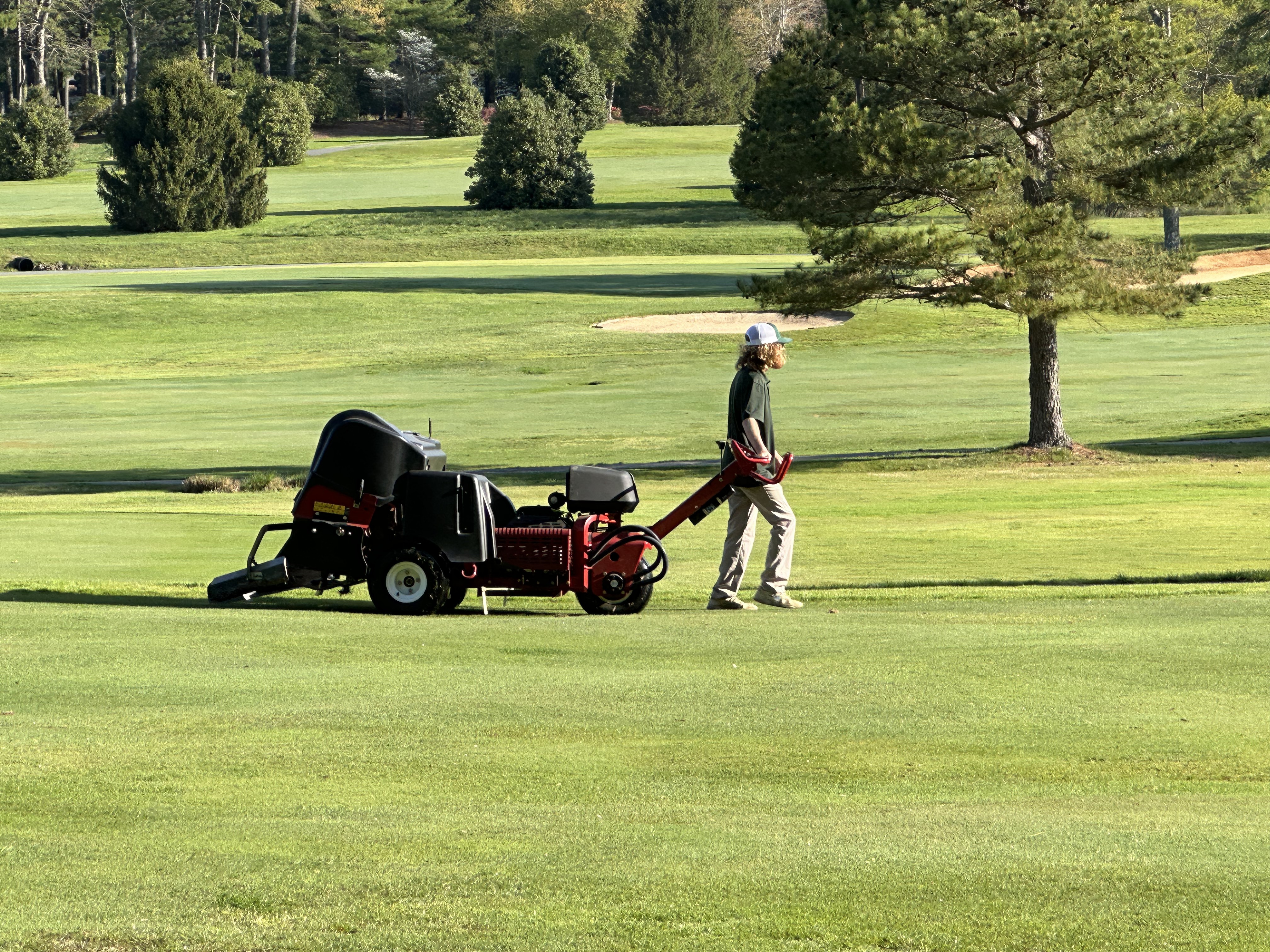 Turf crew member guiding a Toro ProCore 648 across a fairway creating clean rows of aerification holes.