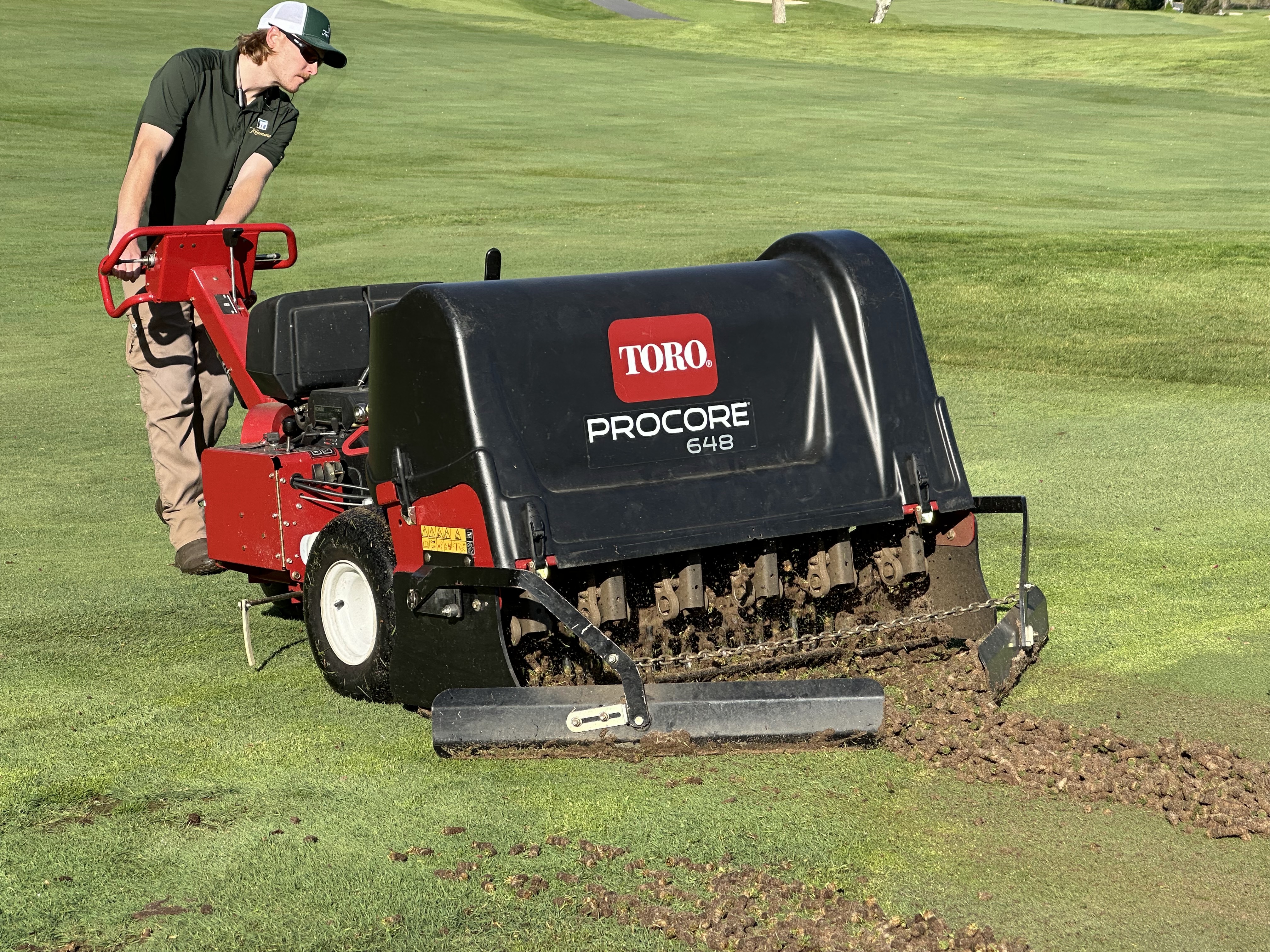 Toro ProCore removing cores as the operator ensures uniform tine engagement and tracking.