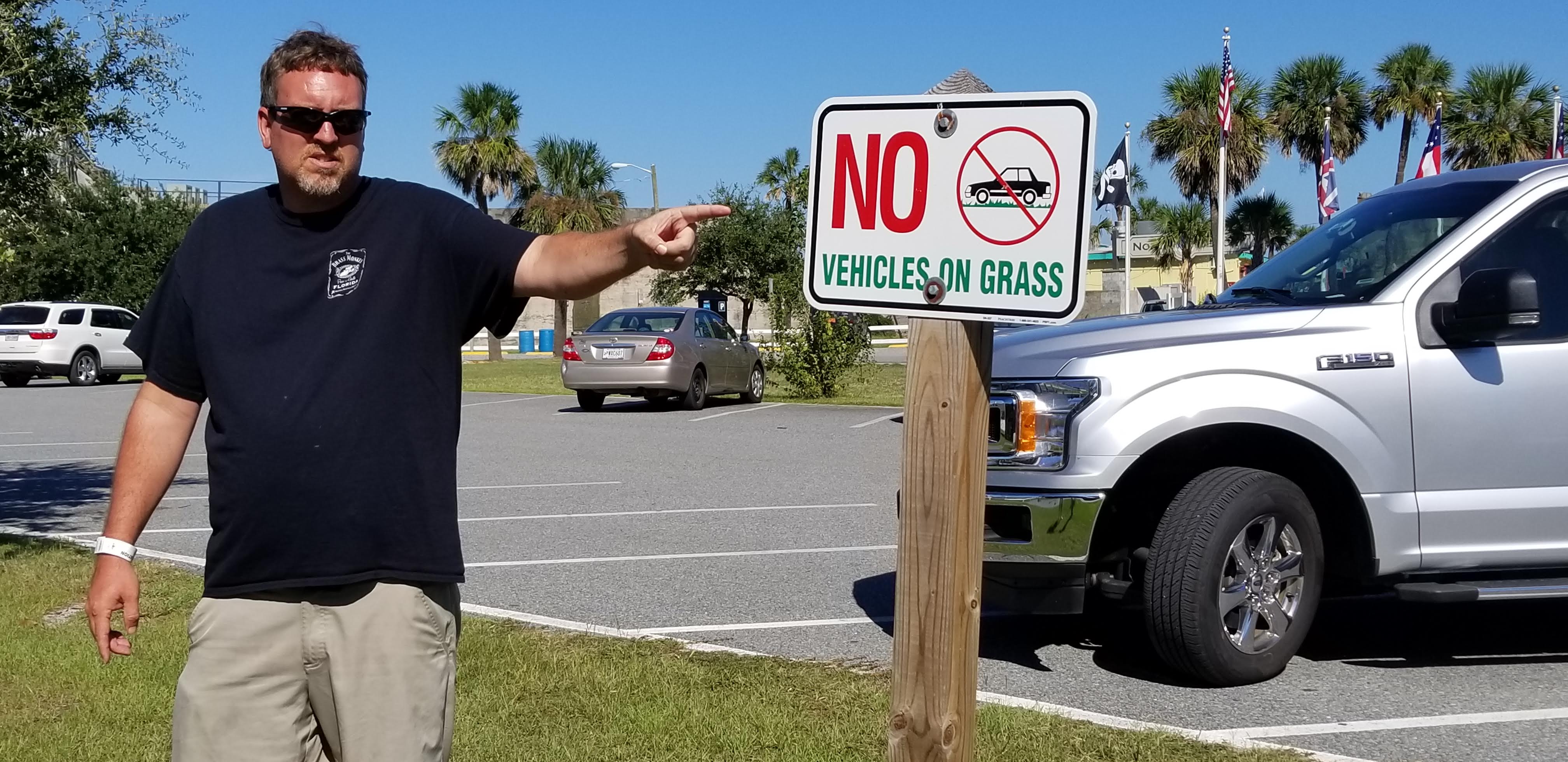 Josh pointing at a sign that says no vehicles on grass